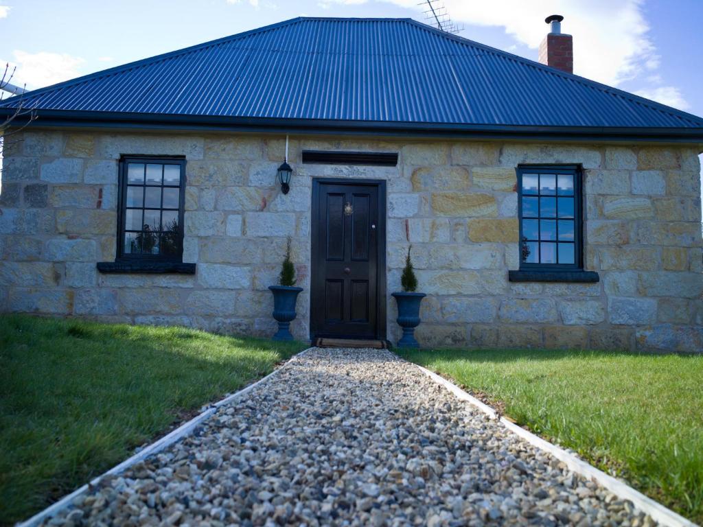 ein Steinhaus mit einer schwarzen Tür und zwei Fenstern in der Unterkunft The Storekeeper's in Buckland
