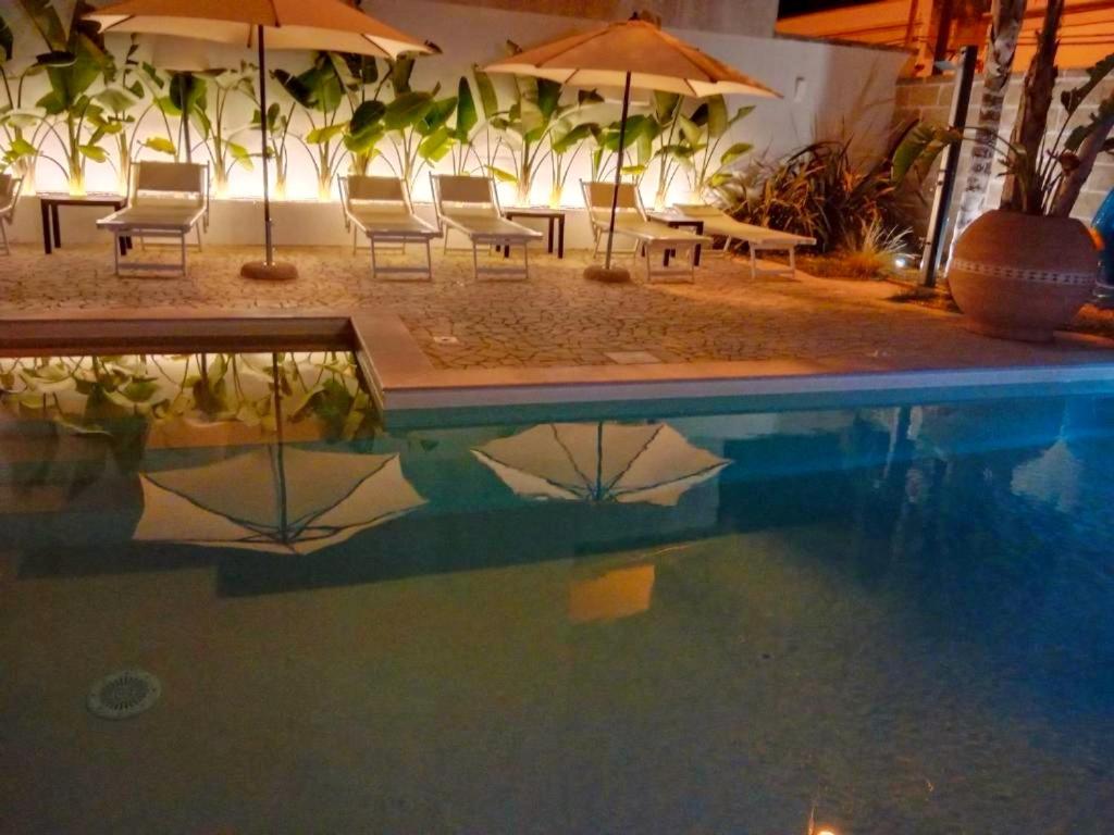 a pool of water with chairs and umbrellas at Vianova Affittacamere in Giurdignano