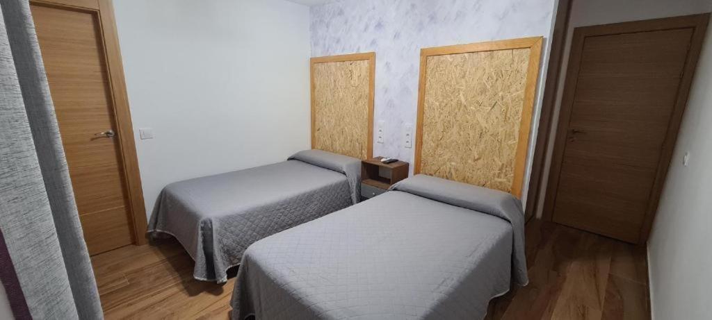 a small room with two beds and two doors at Hostal La Mancha in Ruidera