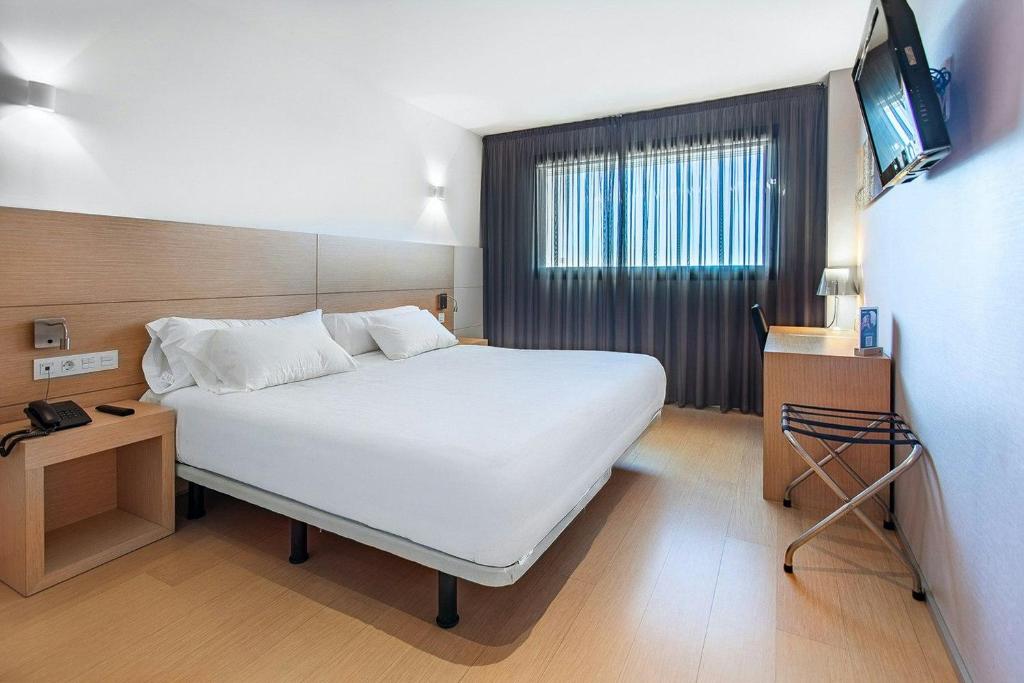 a bedroom with a white bed and a television at Sercotel Hola Tafalla in Tafalla