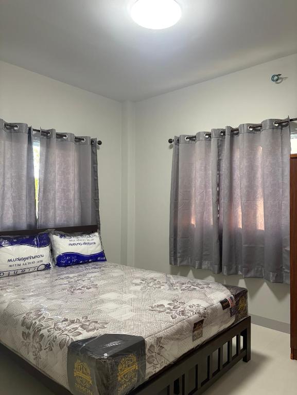ein Bett in einem Zimmer mit grauen Vorhängen in der Unterkunft Mini House in Koh Samui 