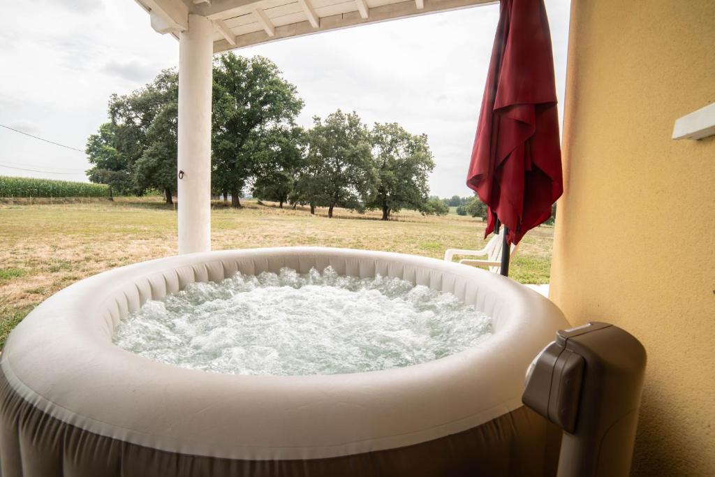 a bath tub with water in it next to a window at L'Horizon des Chênes - grand jardin, bbq & table de ping pong in Hagetmau