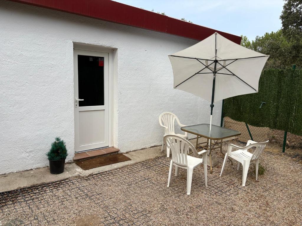 a table and chairs and an umbrella in front of a house at La Casa del Encinar in Valdemorillo