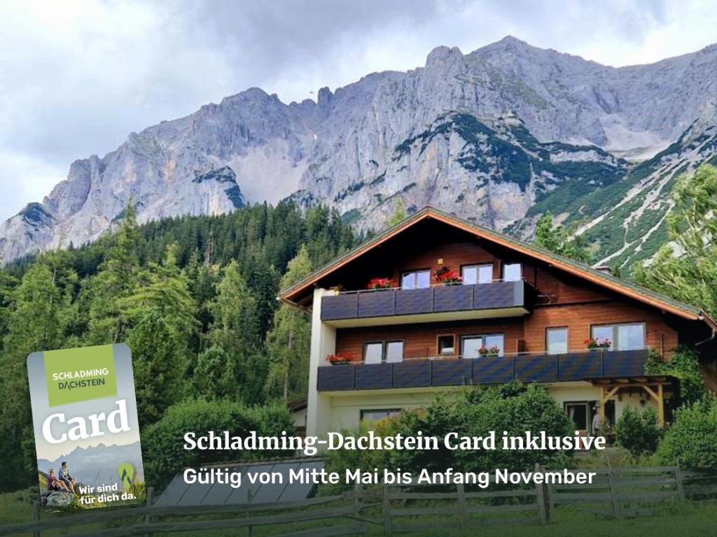 a building with a sign in front of a mountain at Haus Werner, Ferienwohnung mit Sommercard in Ramsau am Dachstein