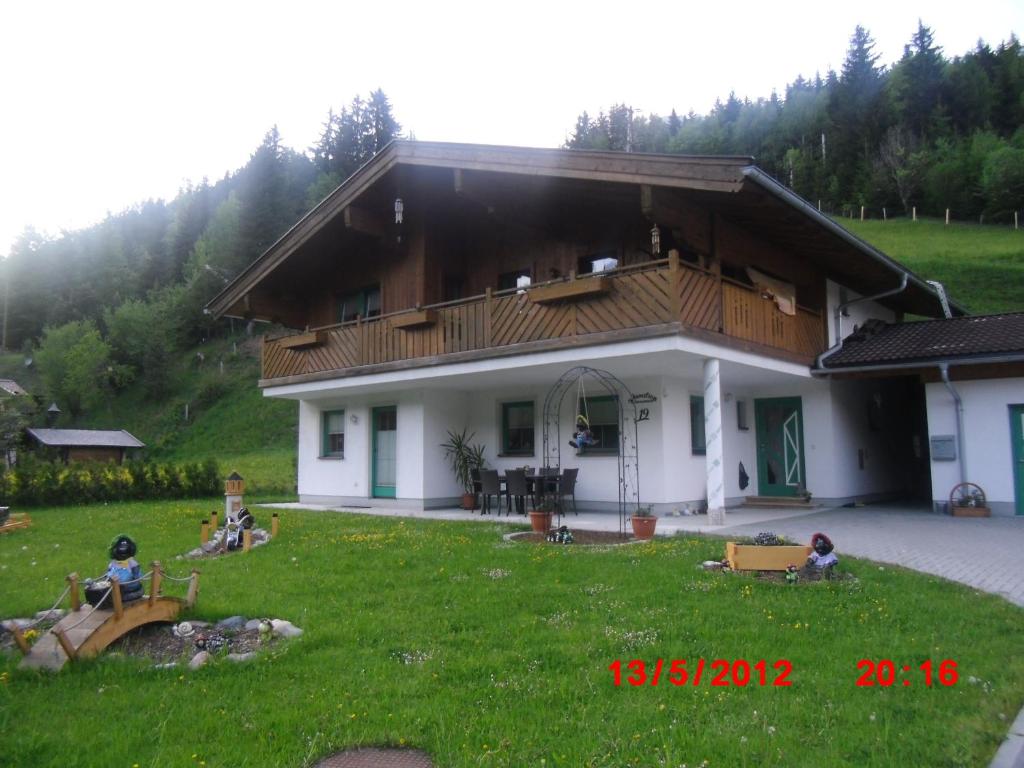 a house with people sitting in the yard in front of it at Appartement Gassner in Leogang