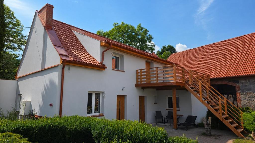 a large white house with a wooden staircase at Dominikówka in Dominikowo