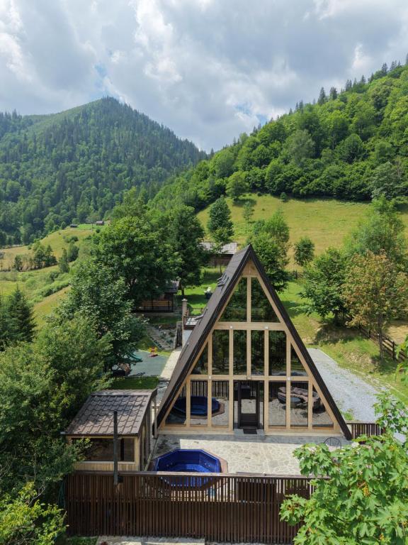 a frame house with a mountain in the background at Ascape Kabin in Broşteni
