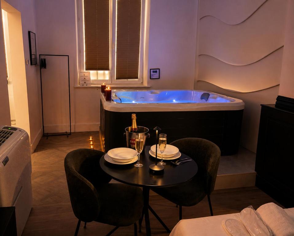 a room with a bath tub and a table with chairs and a table sidx sidx at Le Rêve de Stanislas - Jacuzzi Nancy centre in Nancy
