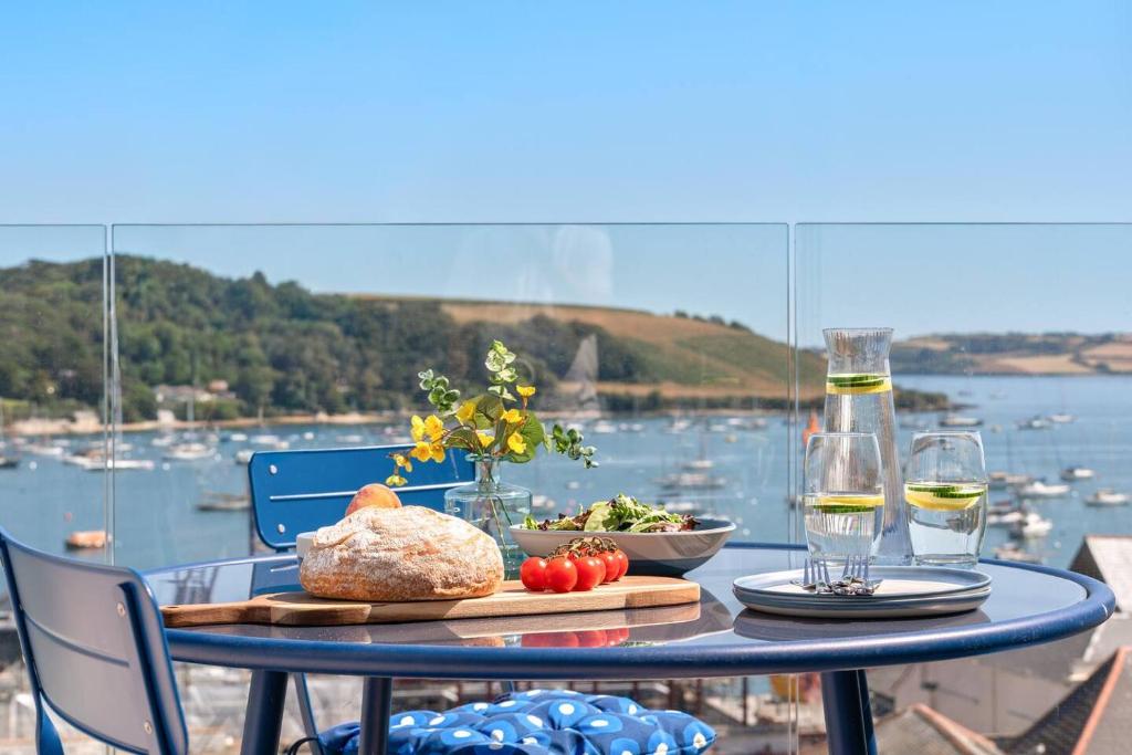 a table with a plate of food and two glasses of wine at Panoramic harbour views Morva in Falmouth