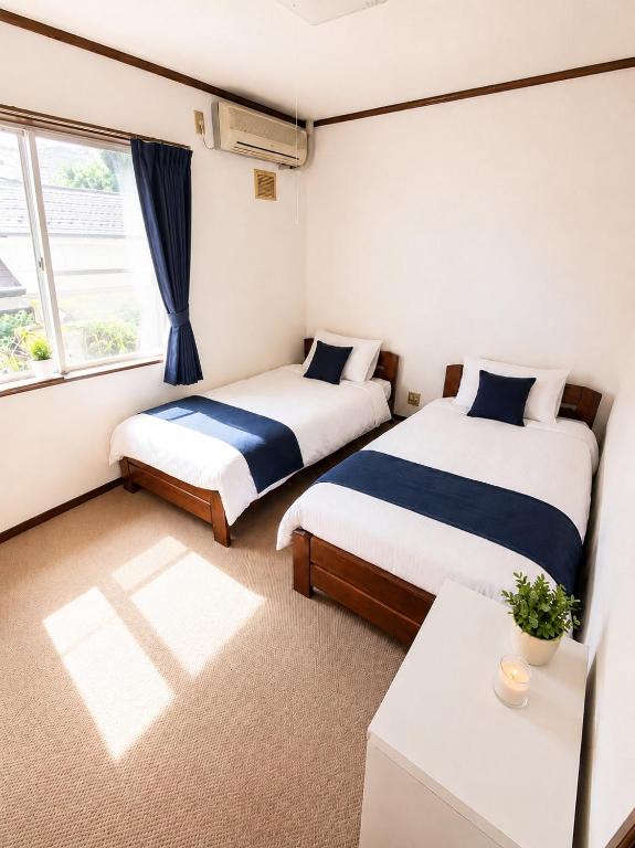 a bedroom with two beds and a window at Heart Warmer in Myoko