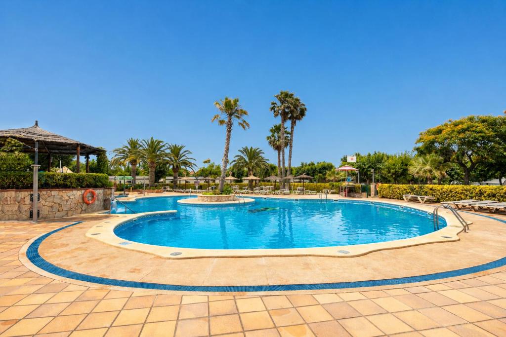 a swimming pool in a resort with palm trees at Kampaoh Blanes in Blanes
