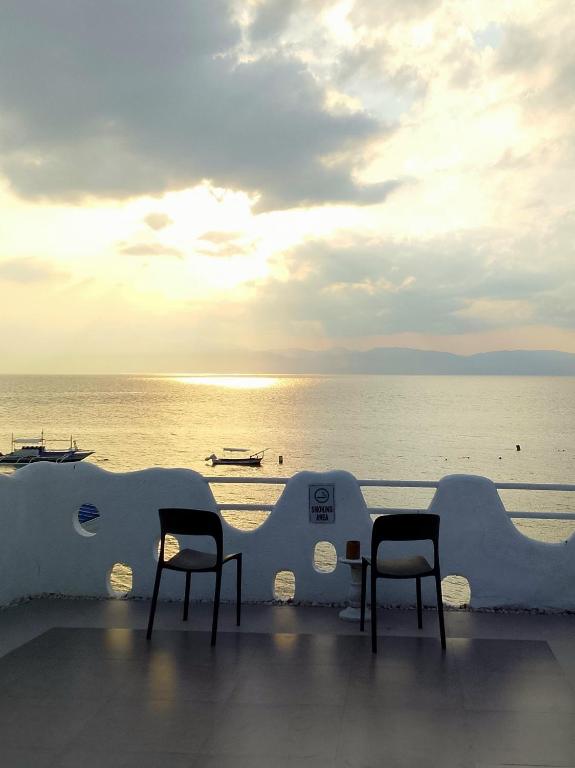 two chairs and tables on a balcony overlooking the ocean at SARDINEBAY Dive Resort in Moalboal