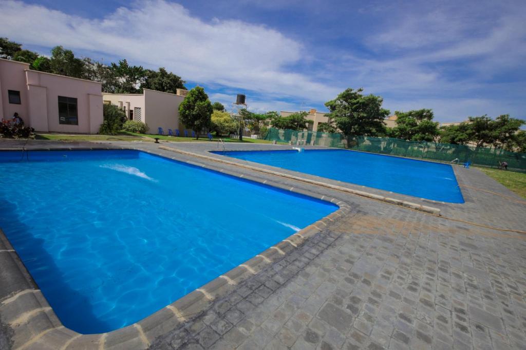 a swimming pool in a villa with blue water at 3 bedrooms Entebbe Lake-House with Pool,Private Beach, Kids Park and AC in Kagolomolo