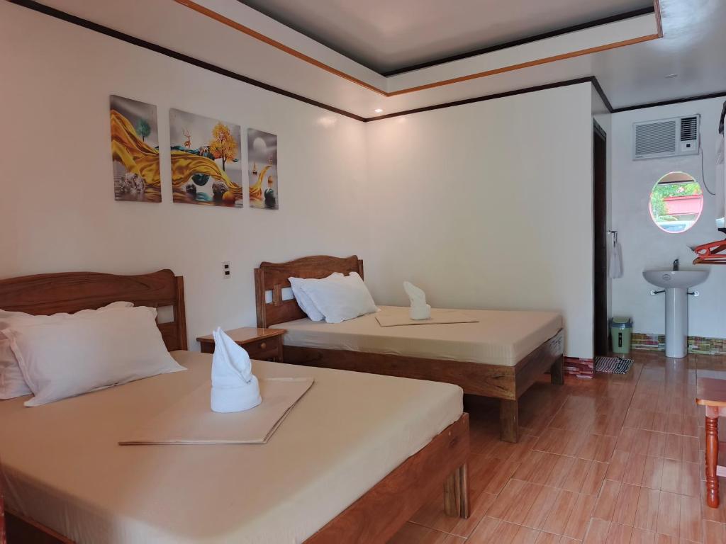 a room with two beds and a sink in it at Rabang Inn in San Vicente