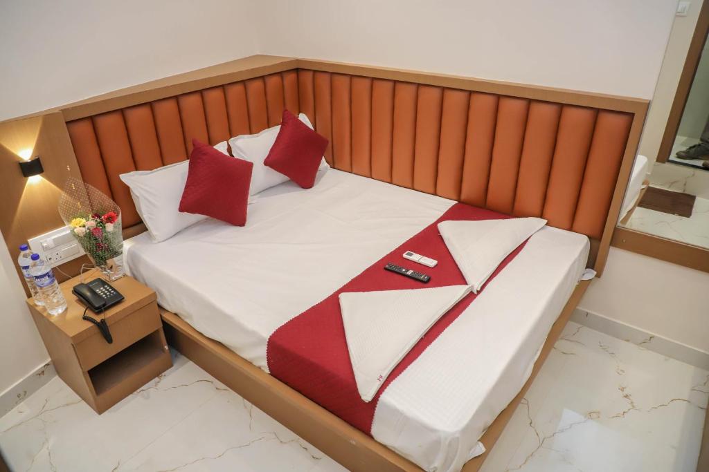 ein Schlafzimmer mit einem Bett mit roten und weißen Kissen in der Unterkunft Hotel Pramila in Mumbai
