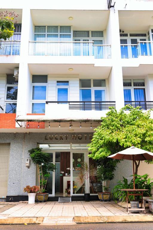 a white building with an umbrella in front of it at Lucky Hotel in Phước Lai