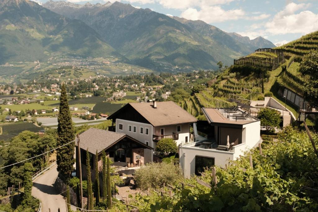 a village on a hill with mountains in the background at Wine Lodge Pratenberg in Merano