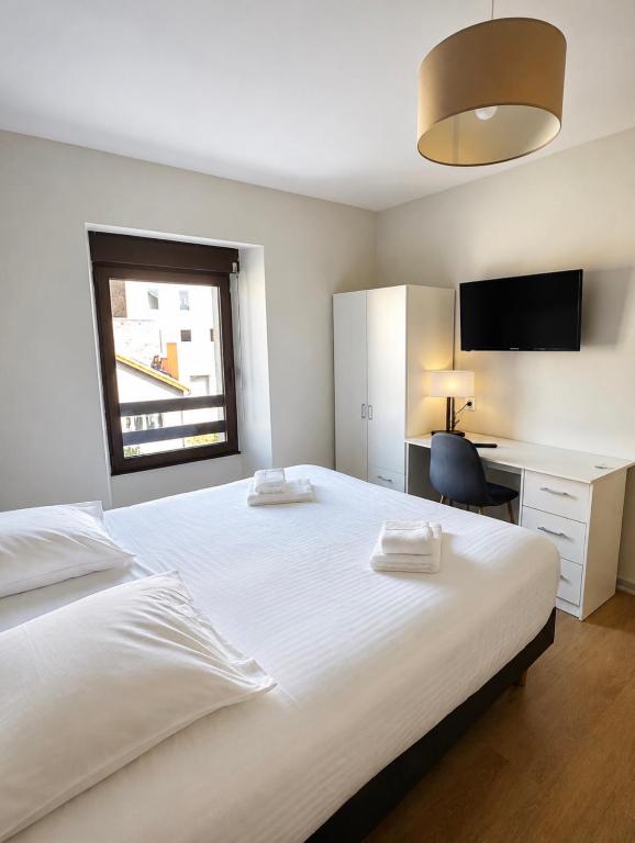 a bedroom with a large white bed and a desk at Apparthotel de Langogne in Langogne