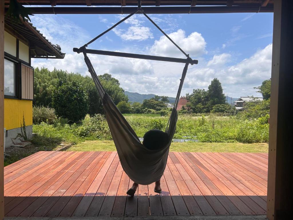 a person sleeping in a hammock on a porch at よんなーハウス in Kameoka