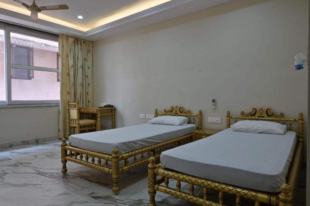 two beds sitting in a room with a window at Iskcon guest house in Patna