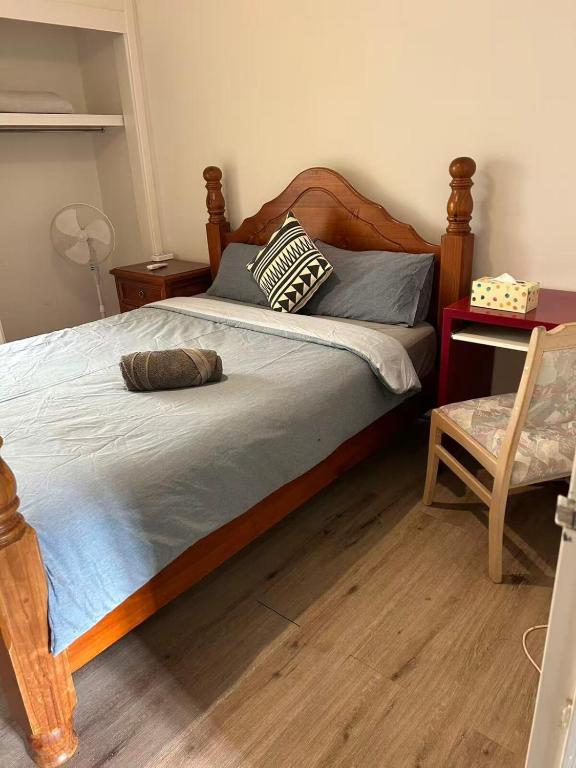 a bedroom with a bed with a wooden frame and a chair at R1 Bright Spacious Room near Perth Airport in Perth
