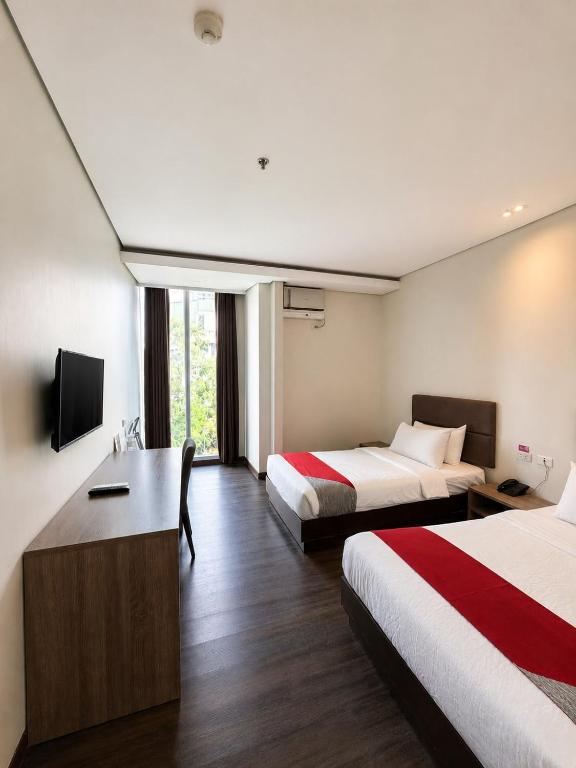 a hotel room with two beds and a desk at Airo Hotel Manila in Manila