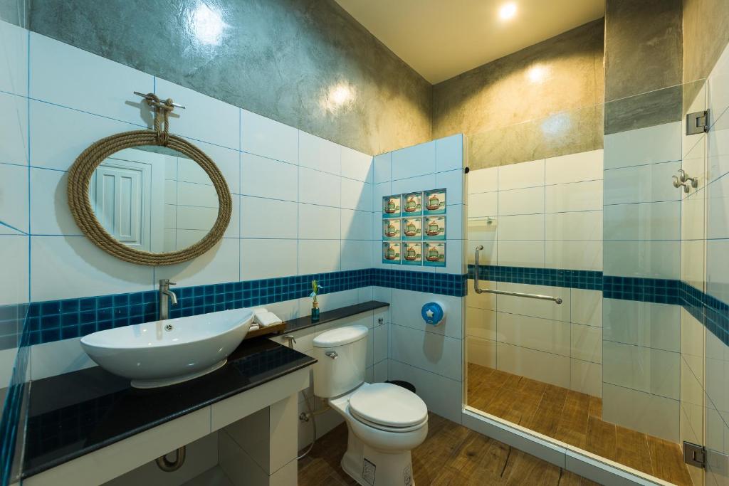 a bathroom with a toilet and a sink and a mirror at The Iconic Hotel Ranong in Ranong