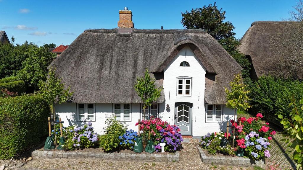 a small house with a thatched roof with flowers at Uns witte Kaat in Oevenum