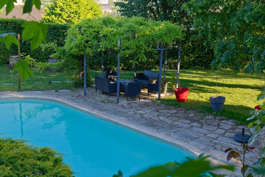 a swimming pool in a yard with chairs and a table at Villla DUO in Besançon