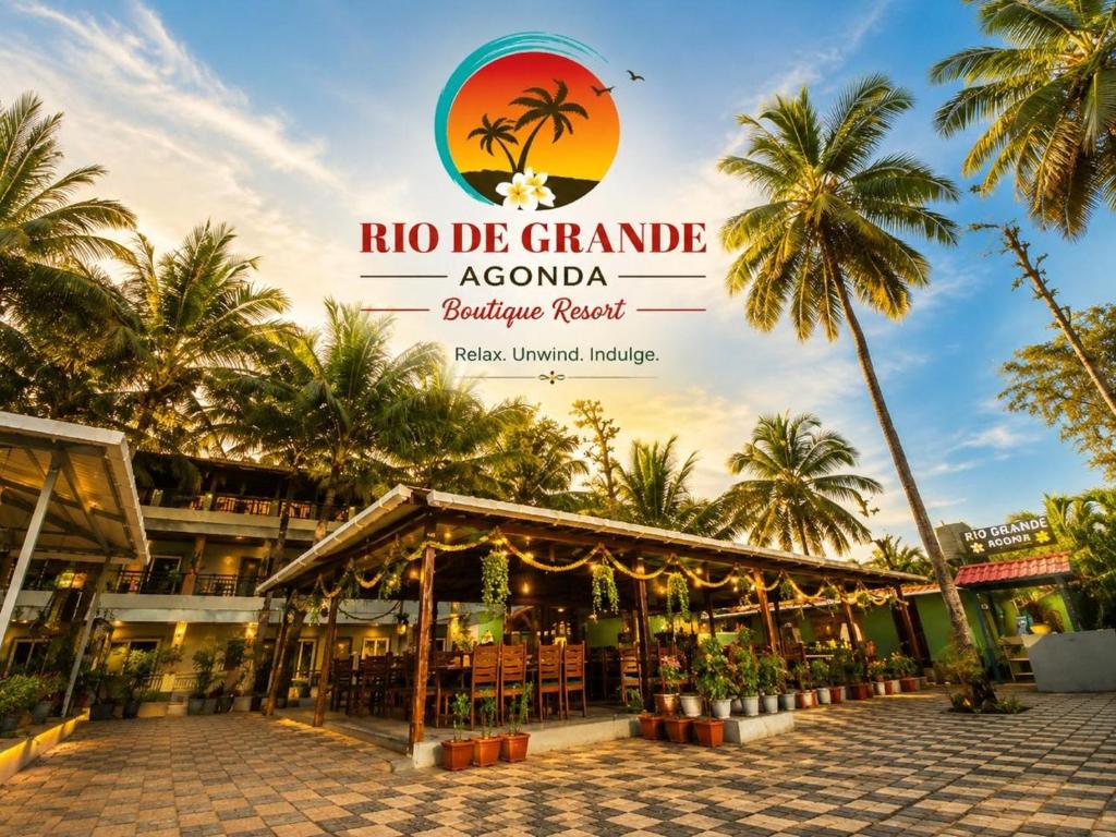 a restaurant in a resort with palm trees in the background at Rio De Grande in Agonda