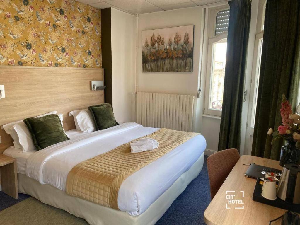 a hotel room with a large bed and a table at Cit'Hotel L'ESCURIAL - Centre Gare in Metz
