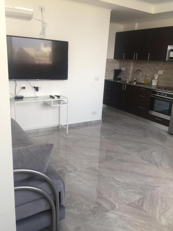 a living room with a tv and a couch and a kitchen at Dizengoff 24A in Netanya