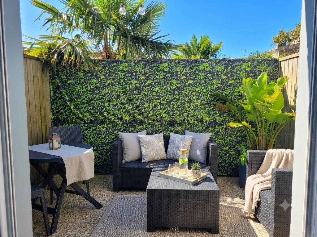 a patio with a couch and a table and a hedge at Notre bout du monde t1bis brest centre terrasse in Brest