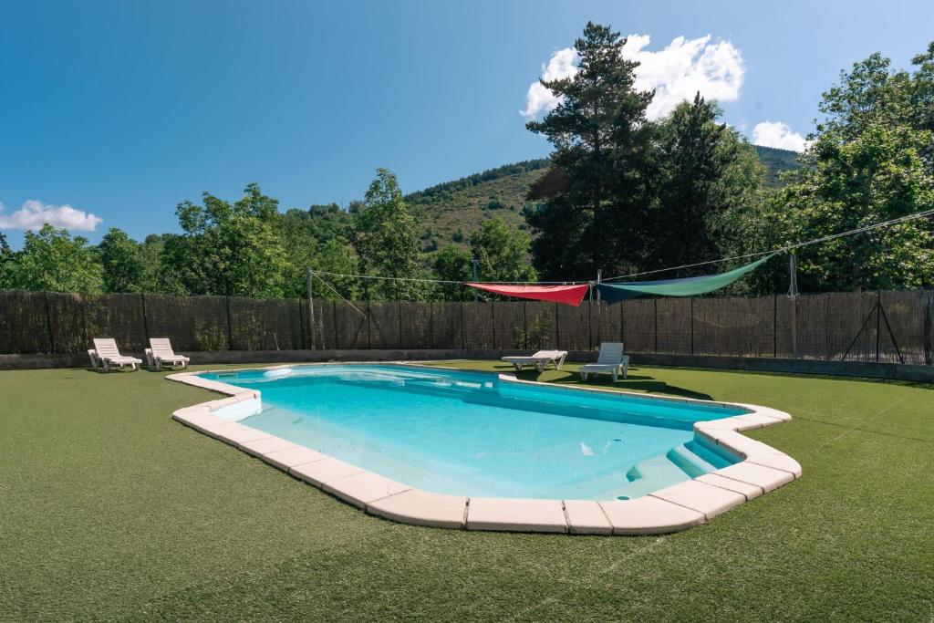 a swimming pool with a hammock in a backyard at Cabaña Le Sapin in Osséja