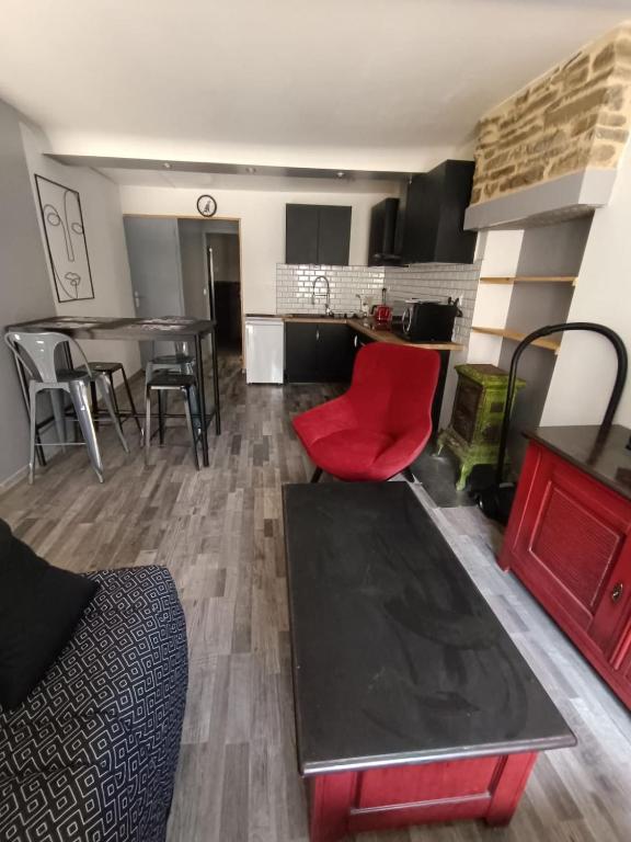 a living room with a red chair and a table at Le Nid d'Ouilly in Pont-d'Ouilly