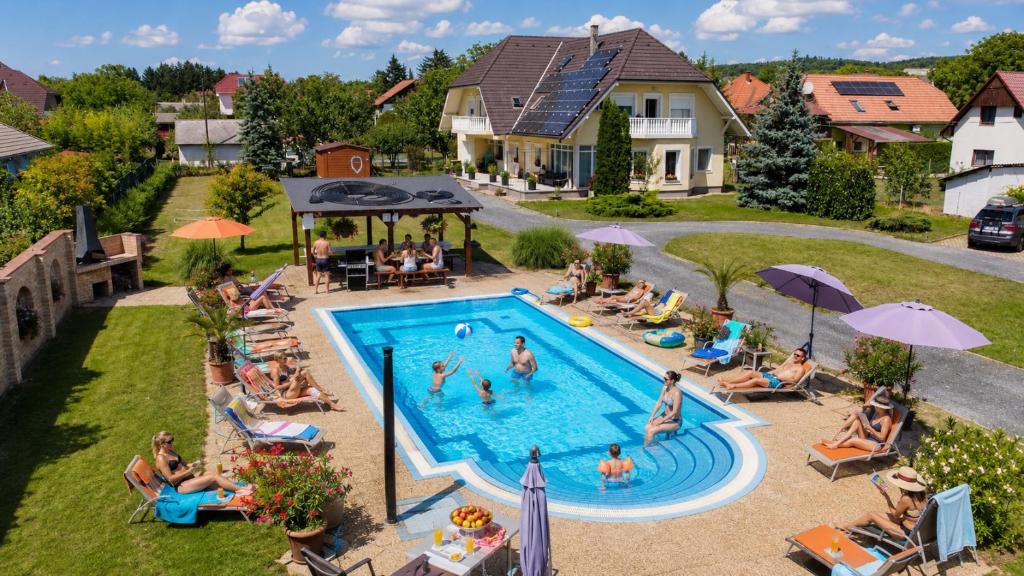 a group of people sitting around a swimming pool at Ilona Apartmanházak in Gyenesdiás