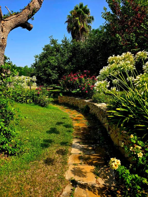 a garden path with flowers and a palm tree at Villa Kepos in Arnesano