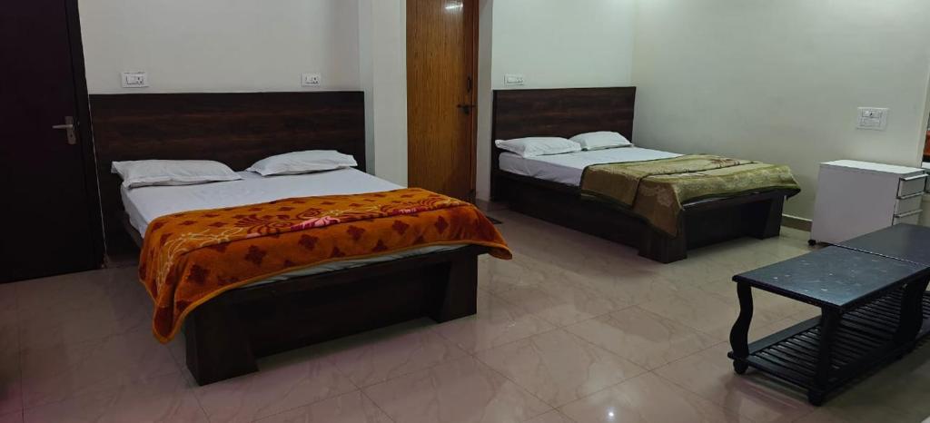 a bedroom with two beds and a table at Shree Ganesh lodging in Bārkūr