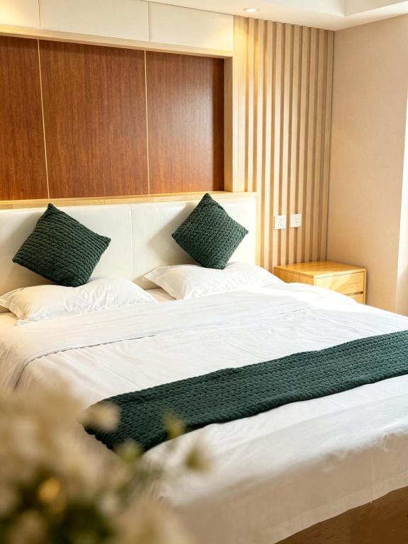 a bedroom with a large white bed with green pillows at zhiyuanta hotel in Vientiane