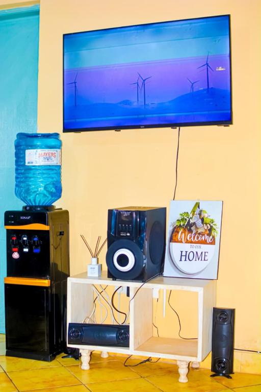 a room with a table with a speaker and a tv at Diani Escape in Ukunda