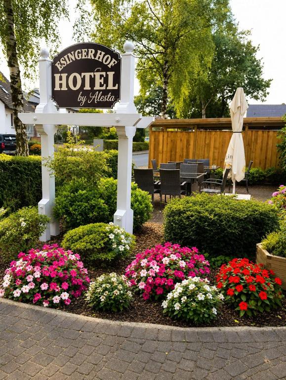 a sign for a hotel with flowers in a garden at Hotel Esingerhof by Alesta in Tornesch
