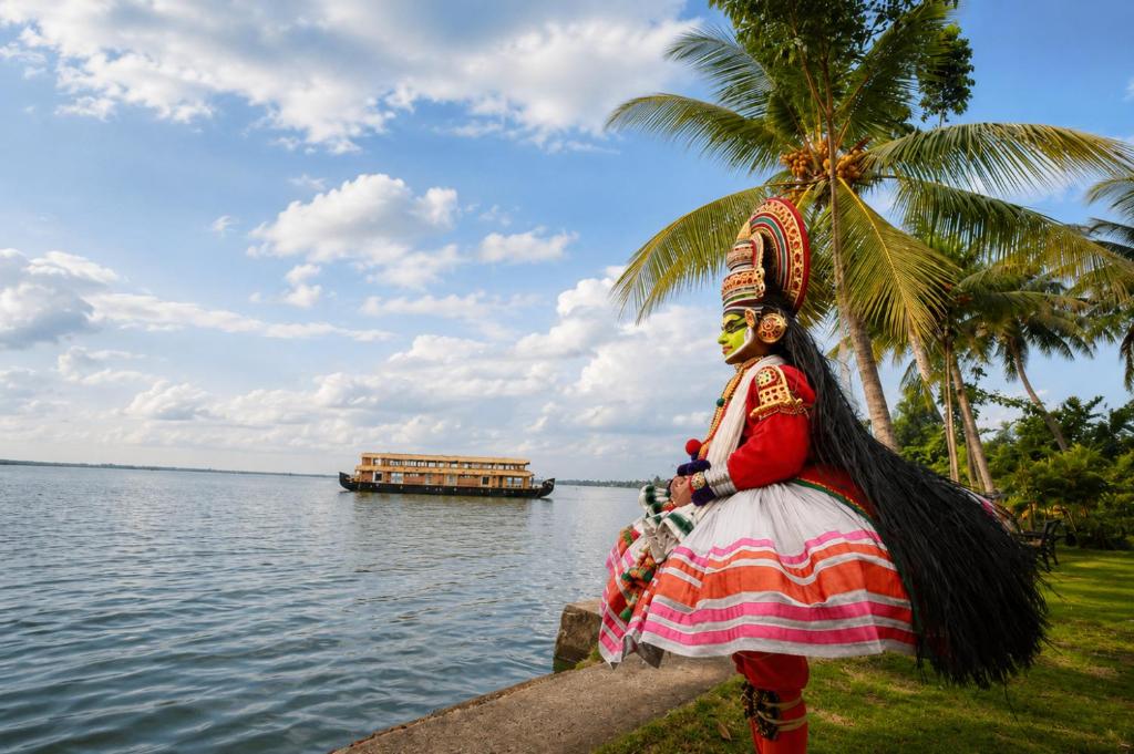 a woman in a dress standing next to a body of water at Southern Panorama Houseboats in Alleppey