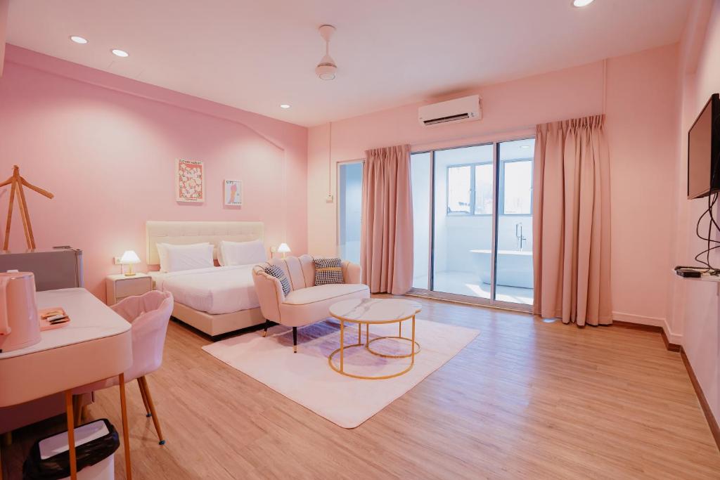a bedroom with a bed and a living room at Hugstore Pink Hotel in George Town