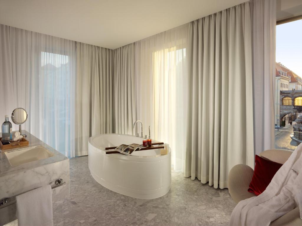 a white bathroom with a tub and a large window at HYPERION Hotel Dresden Am Schloss in Dresden