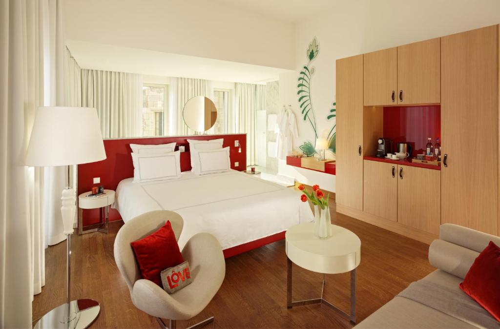 a bedroom with a bed and a chair and a couch at HYPERION Hotel Dresden Am Schloss in Dresden