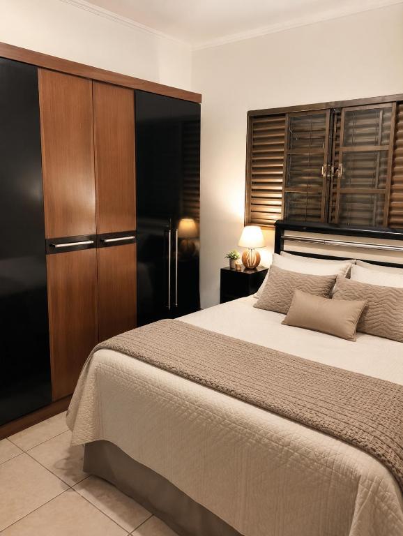 a bedroom with a large bed and a wooden cabinet at Balcony house in Campo Grande