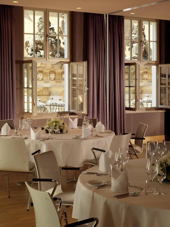 a restaurant with white tables and chairs and windows at HYPERION Hotel Dresden Am Schloss in Dresden