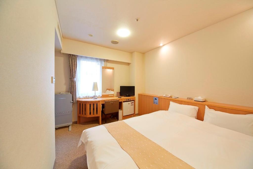 a hotel room with two beds and a television at Nest Hotel Kumamoto in Kumamoto