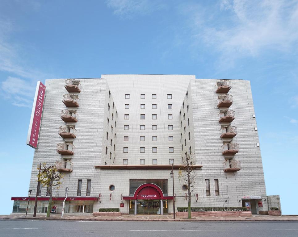 a white building with balconies on the side of it at Nest Hotel Kumamoto in Kumamoto
