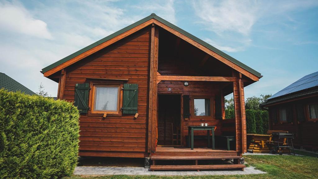 a small wooden cabin with a window and a table at Domki Letniskowe Krakus in Rusinowo